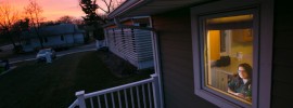 Julie Glenn, a senior in biological sciences and secretary of the Solar House Team, watches the sunset from the front window of her solar house.